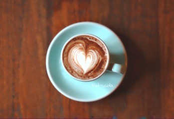 Hot chocolate heart latte art  in blue cup on wooden table.
