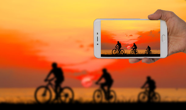   Tourist taking a picture of blur image of group friend  and bike relaxing on red sky  background.