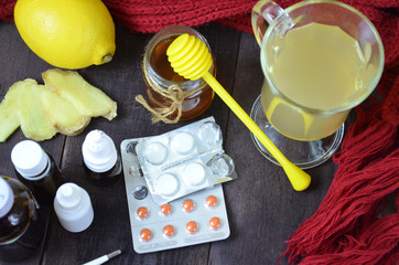 healthcare, traditional medicine and flu concept - tea cup with lemon, ginger, honey and pills on wooden table. tablets, pills, cough syrups, nasal drops and non-traditional alternative medicine.