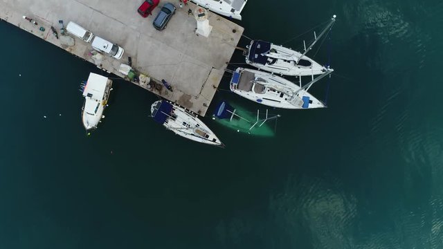 Aerial view. A small sailing yacht sank near the pier. Mast sunken boat sticking out of the water near the quay.