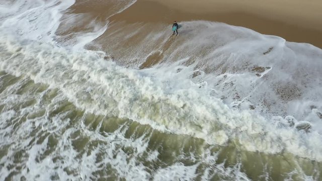 Orbiting a surfer standing on the beach.