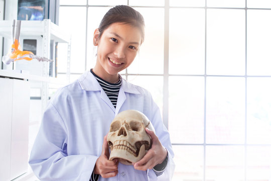Young Asian school girl holding a skull model in the laboratory, education and orthopedic concept