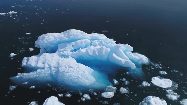 Aerial Flight Over Huge Iceberg In Antarctica Ocean. Drone View From Above Ice Mount Floating In Clear Water. Winter Polar Ocean Scape. Harsh Environment. Permafrost. 4k Footage.