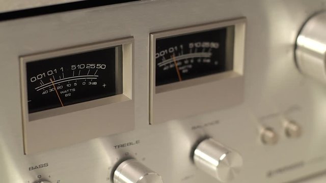 Close up panning footage of vintage record player with analog needle indicators.