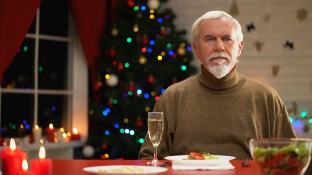 Sad man celebrating Xmas alone, looking to camera, social services for retirees