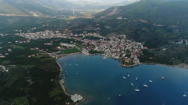 Aerial view of the town of Epidavros among the mountains on the shore of the picturesque Bay with many boats on the anchorage from a great height.