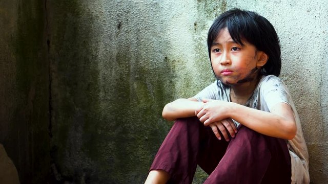 Young Southeast Asian dirty homeless boy looking into the distance longingly wishing for a normal life
