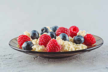Cottage cheese with fresh raspberries and blueberries in a plate for a healthy breakfast with ripe berries. A natural healthy product.