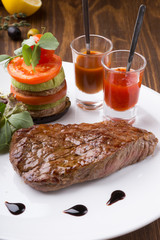 Fried juicy beef steak served with grilled vegetables and spicy sauces