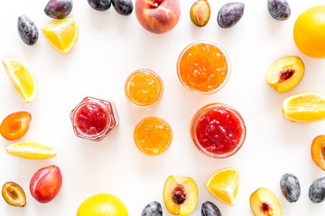 Jams different tastes made of fruits and berries near pieces of fruits on white background top view