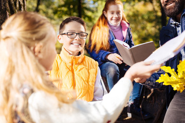 With a class. Joyful happy boy smiling while having a tour in the forest with his class