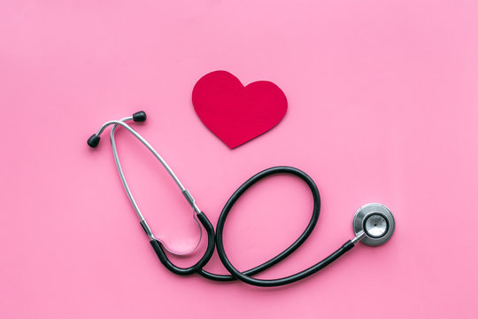 Heart disease concept. Stethoscope near heart sign on pink background top view