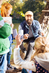 Saving planet. Delighted nice man being surrounded by children while teaching them about alternative energy