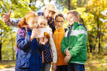 Nature photographer. Serious red haired girl holding a tablet while wanting to take a photo of the...