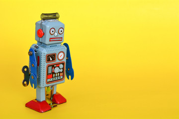 Vintage tin toy robot isolated on a yellow background.
