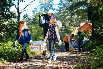 Mutual help. Pleasant nice girls walking along the path while carrying a heavy box together