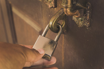 The old wooden door is locked with a silver lock, unlocked with a hand lock.