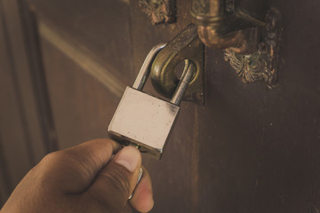 The old wooden door is locked with a silver lock, unlocked with a hand lock.
