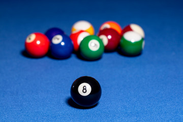 Black billiard ball with number eight. Background out of focus.