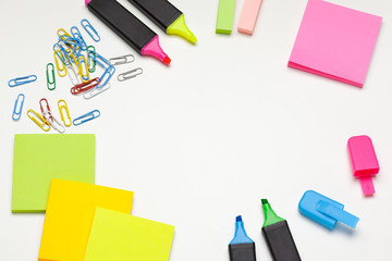 Sticky notes with markers, colored pens, paper clips laying on a table