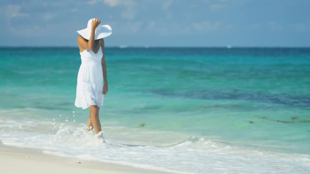 Beautiful ethnic Hispanic girl wearing white dress on ocean beach 