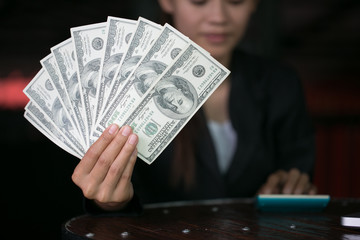 Business woman displaying a spread of cash over,  spending money or profit from business operations concept