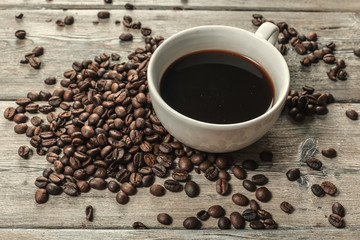 Cup of coffee and beans on wooden background