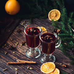 two glasses with mulled wine on the table with orange slices and spices with winter Christmas decor