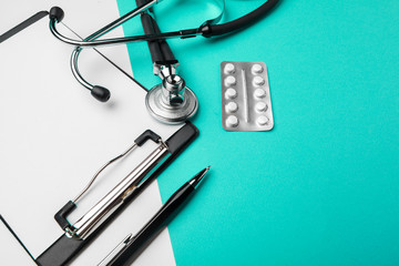 Stethoscope, clipboard and pills, closeup. Medical equipment