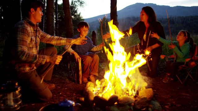 Happy American Caucasian family making campfire in nature on holiday outdoor