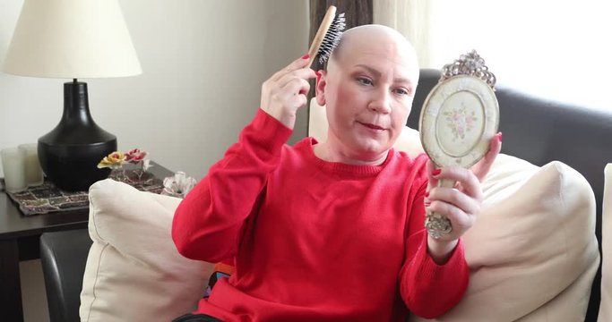 Mentally ill woman with bald head looking at the mirror and brushing her hair