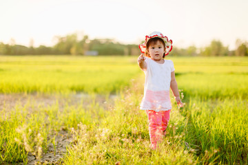 Fototapeta premium Asian toddler girl exploring natural environment in the rice field. Outdoor activity like play, touch and see the real things is the best learning method for baby and kids.