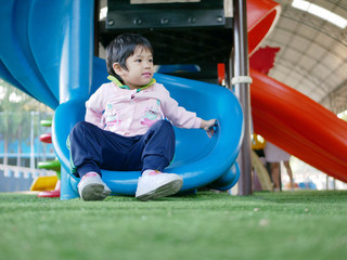 Fototapeta na wymiar Little Asian baby girl, 34 months old, being happy after sliding down a slider by herself