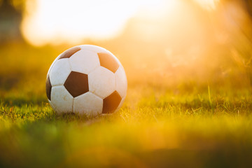 Fototapeta na wymiar A ball on the green grass field for soccer football game under the sunset ray light.