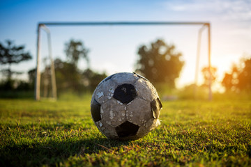 A ball on the green grass field for soccer football game under the sunset ray light.
