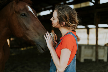 Happy girl grooming a chestnut horse