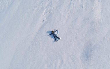 Woman makes snow angel laying in the snow. Top view. Aerial foto.