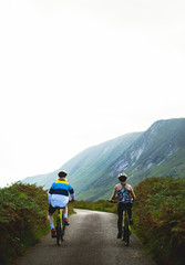 Obraz premium Couple cycling down a road in the Scottish Highlands