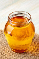 A closeup photo of a jar of honey on a rustic background with a place for text