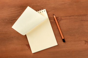 Turning a New Page. A photo of a spiral notepad with a blank sheet of paper, shot from above on a wooden background with a pencil and a place for text
