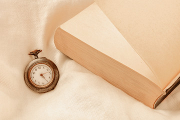 Page-turner Concept. A watch showing early morning hours and a finished book on a pillow. Impossible to put down the book. Toned Image