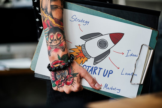 Tattooed hand holding a startup clipboard