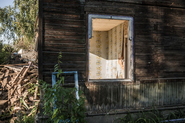 Old ruined wooden house. Two-story building intended for demolition. Summer day