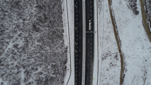 aerial top view of highway with low traffic on snowy winter day