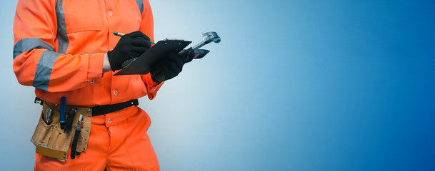 The measurer worker writes dimensions to his notebook. Building contract signing. Builder with construction project plans in the hands isolated on blue background.