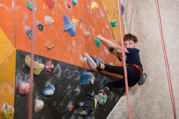 Obraz na płótnie Canvas little boy climbing a rock wall 