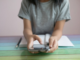 Fototapeta premium A little girl playing smartphone with doing homework