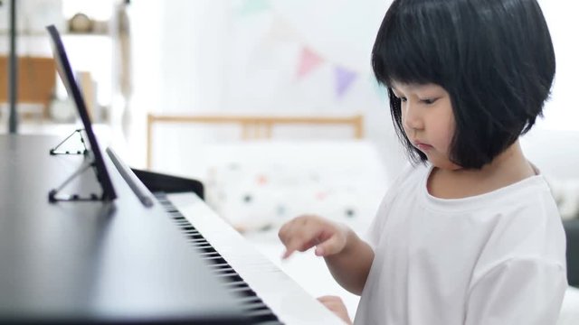 4K Happy little Asian girl playing piano 