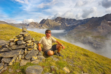Naklejka na ściany i meble Resting tourist on the ridge next to the stone pile with mountains on backround, Pyrenees