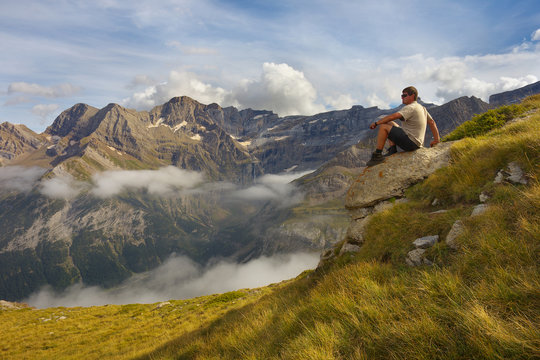 Resting tourist sitting on the stone with mountains on backround, Pyrenees